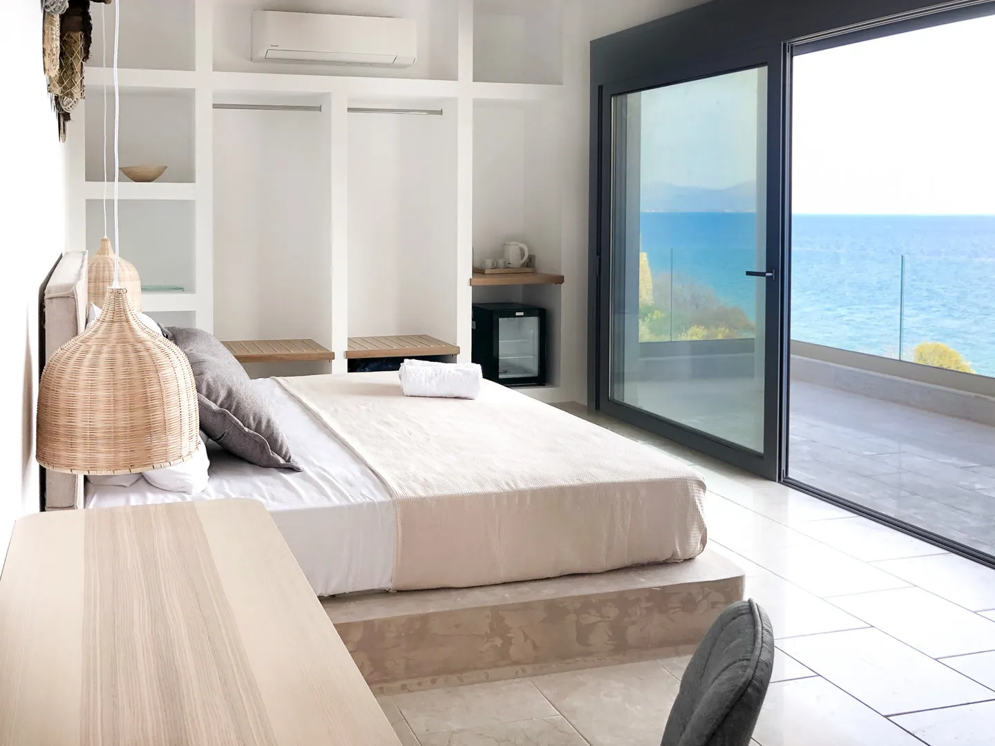 Zephyros bedroom with king-size bed on a stone platform, opening to a sea-view terrace