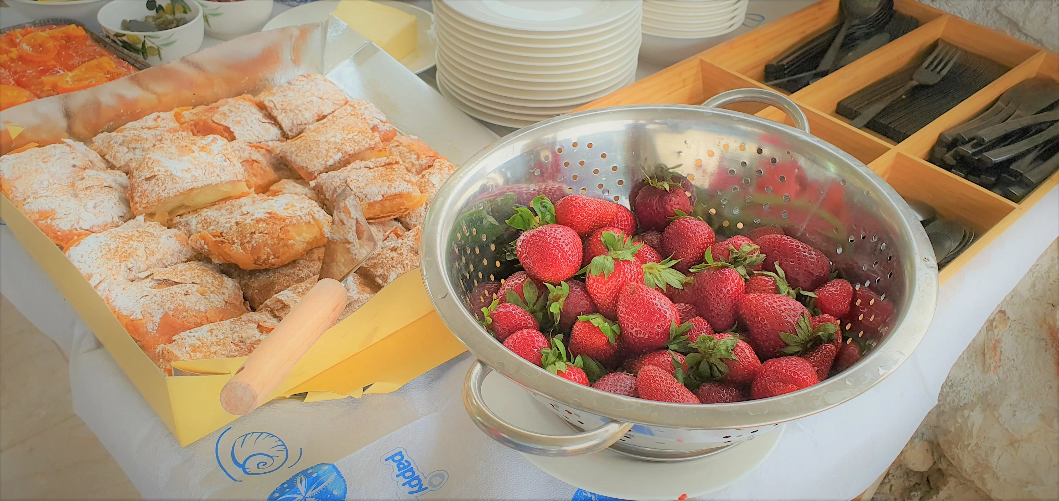 Fresh strawberries and breakfast dishes on the outdoor table