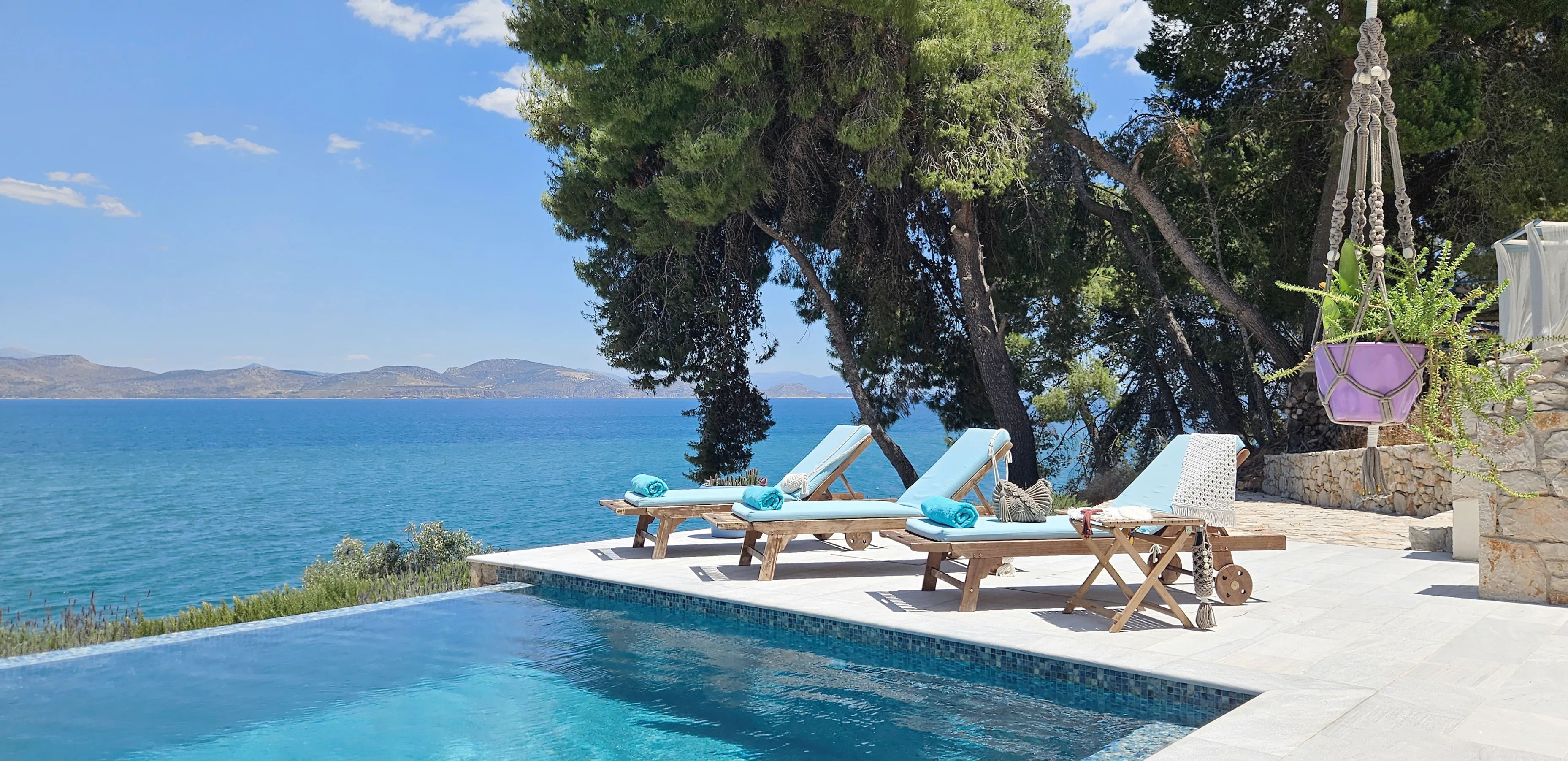 Loungers with turquoise cushions at the pool under the pines