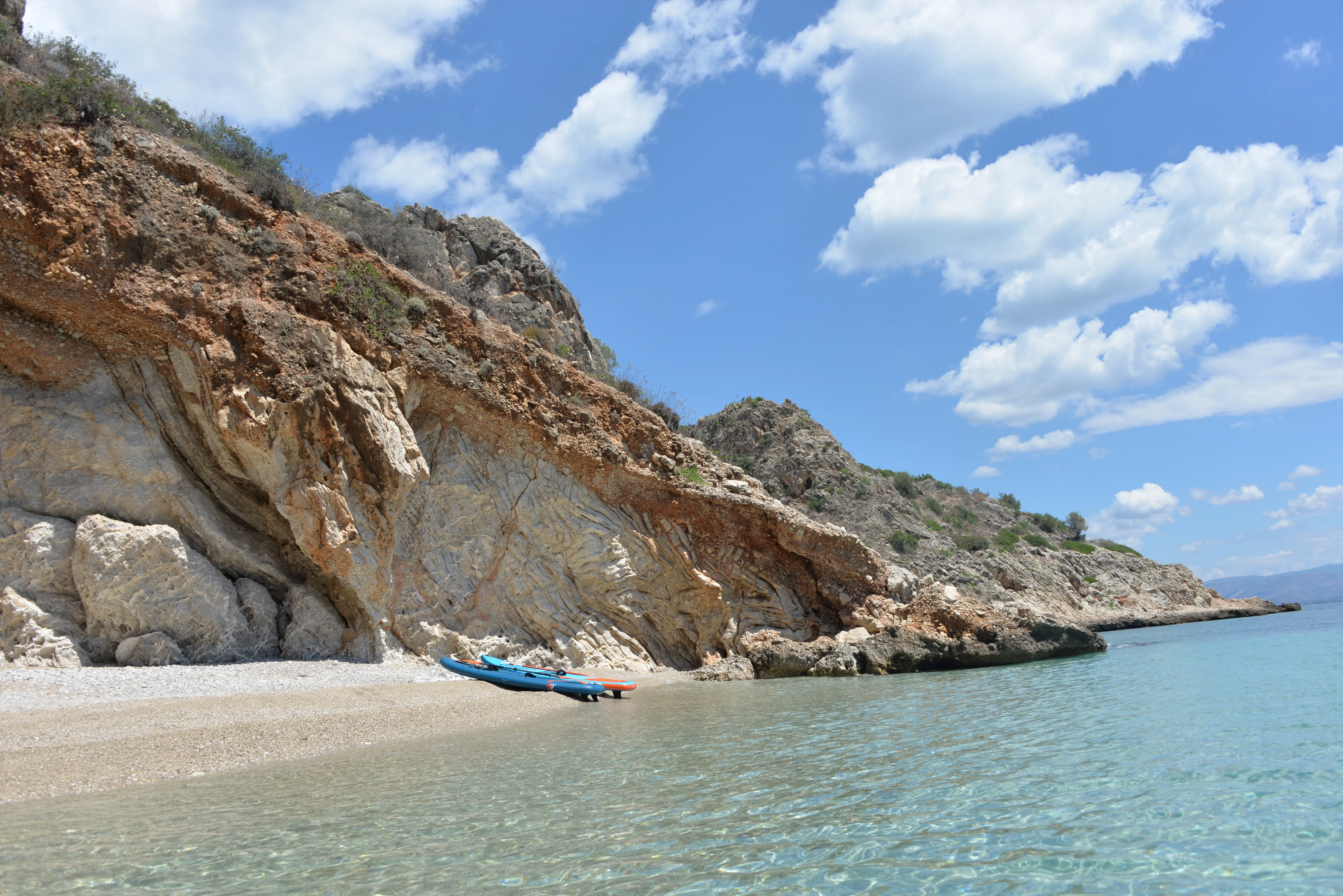 Paddleboard pulled ashore at a cove of clear shallow water