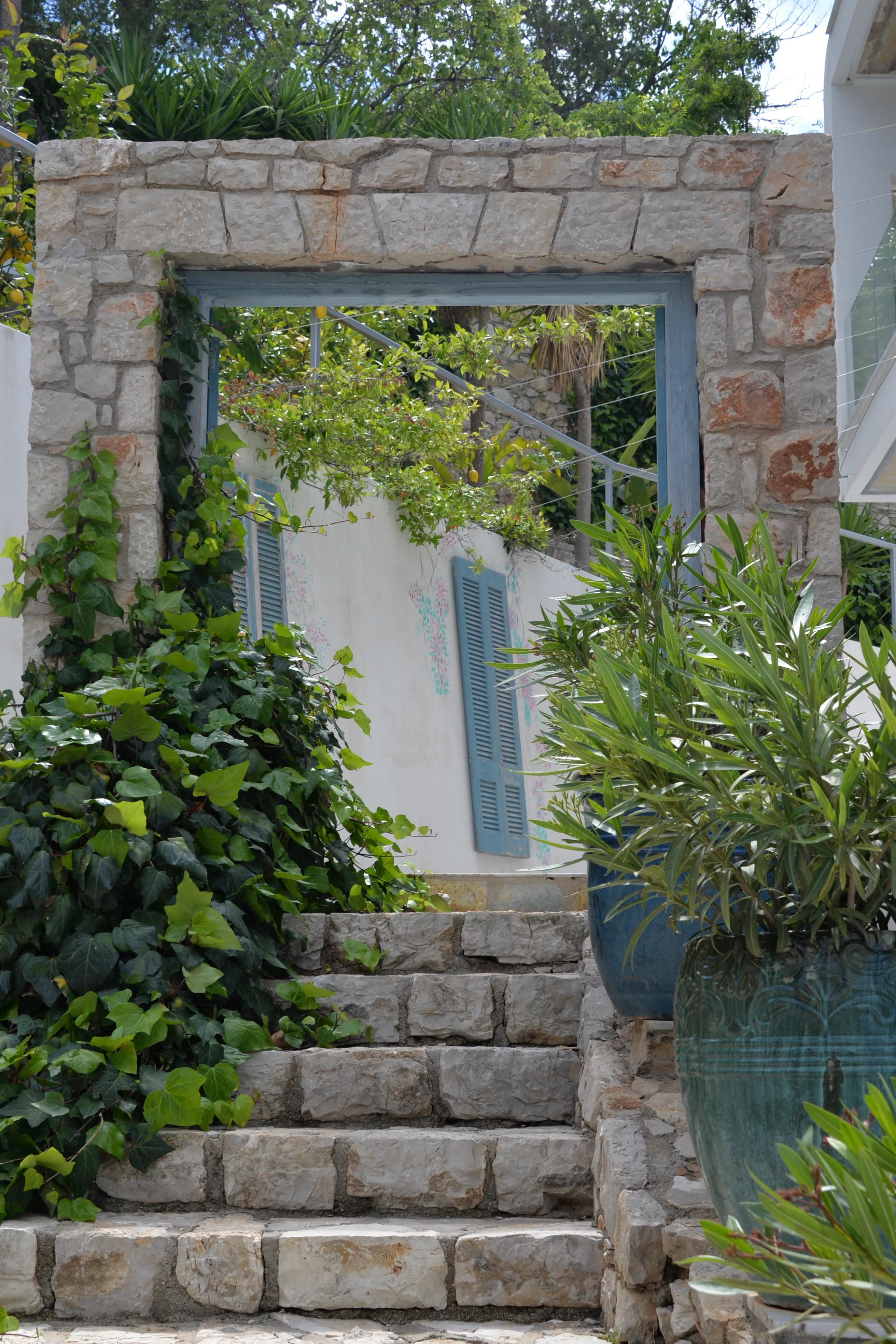 Stone wall with climbing greenery and a framed mirror