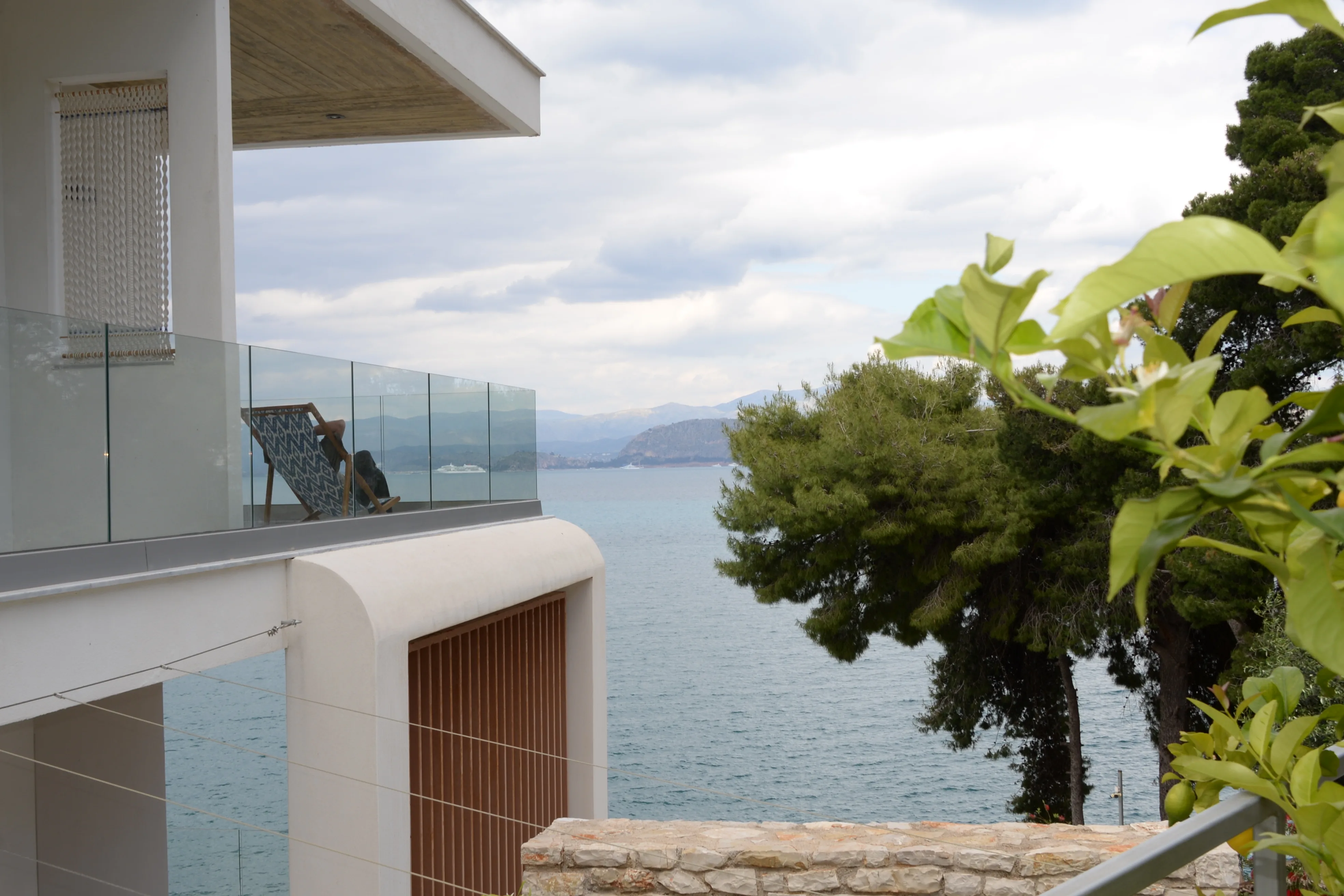 Balcony with glass balustrade among the pines, sea below