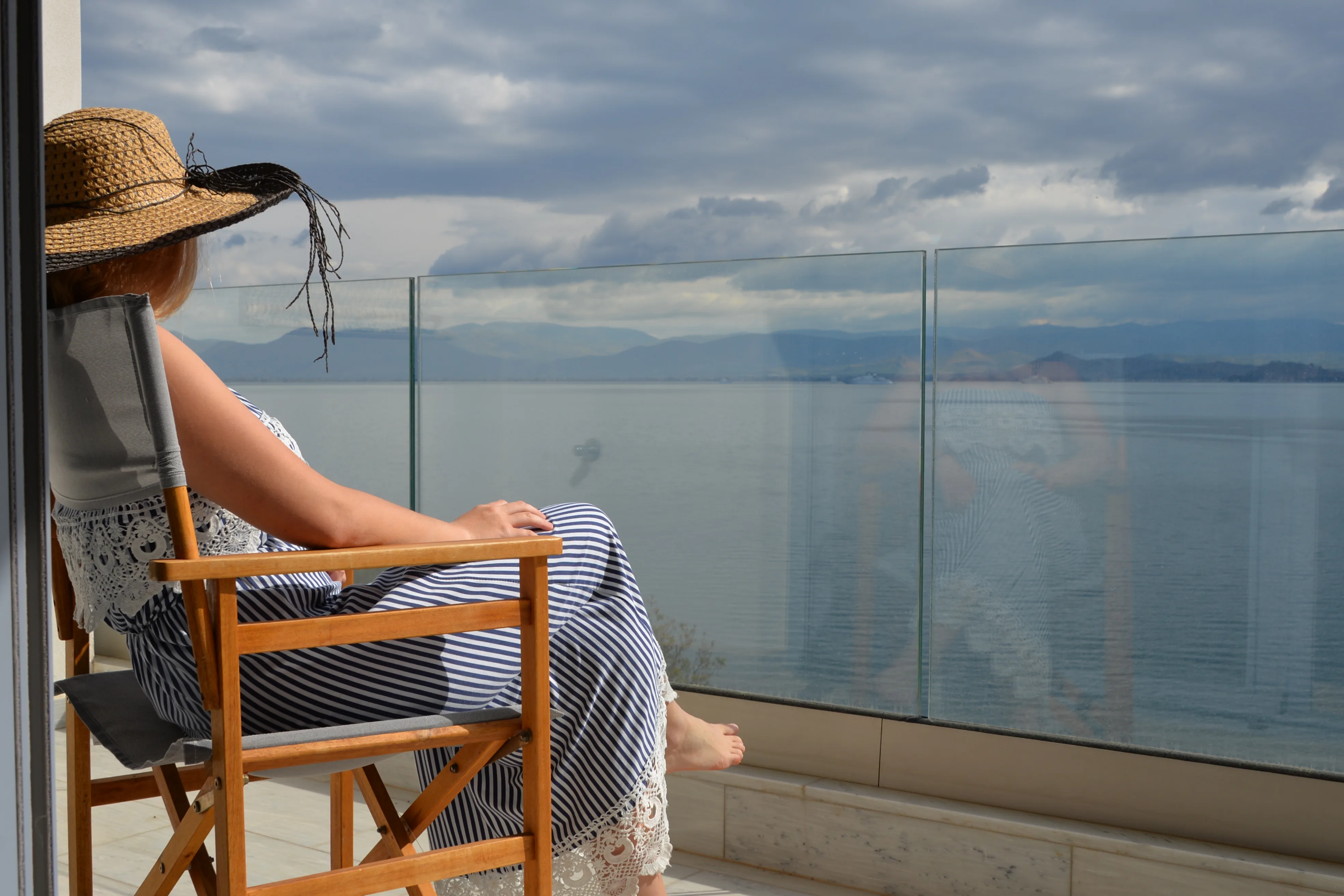 Guest reading on a balcony chair behind the glass balustrade