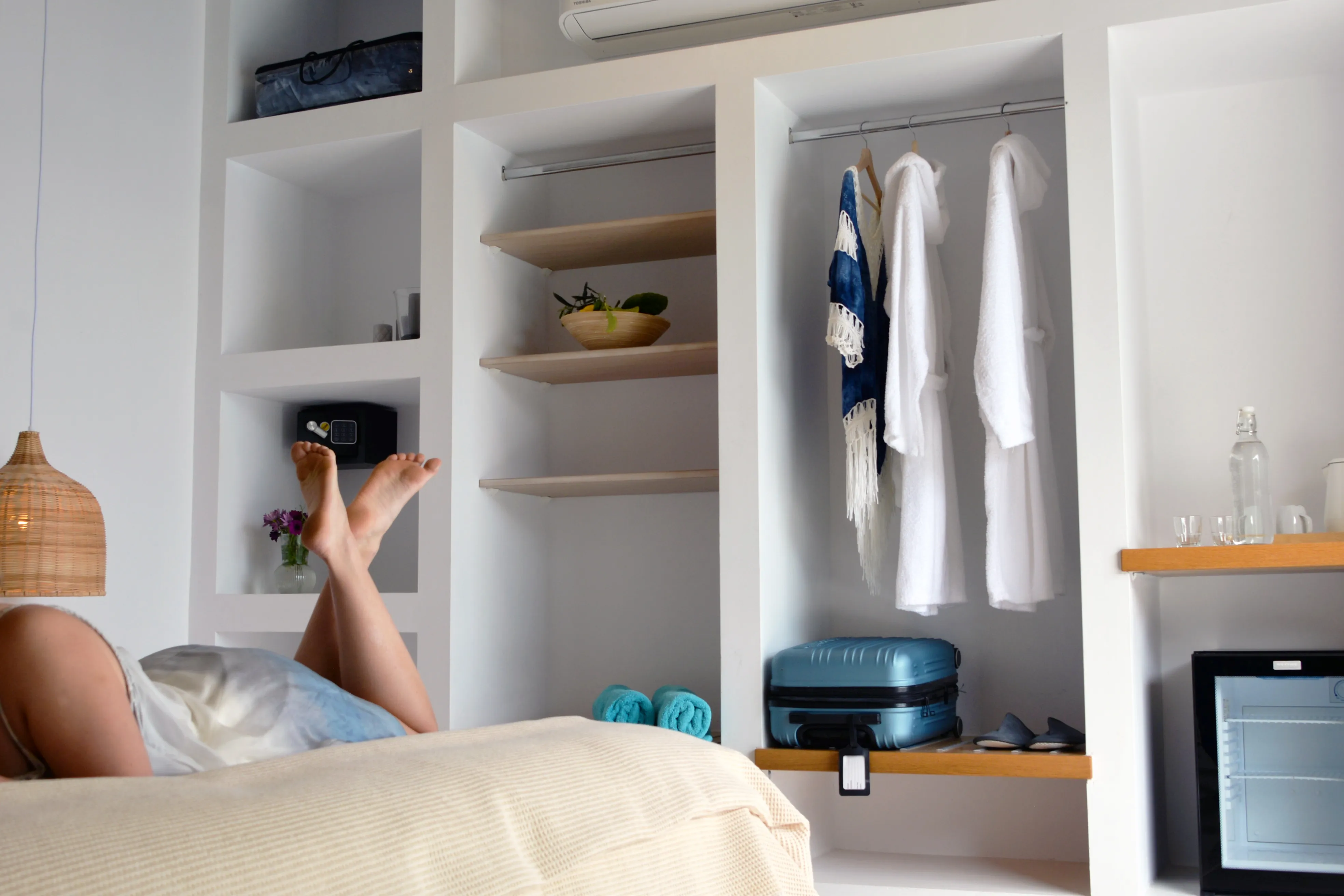 Guest resting on the bed beside open wardrobe shelving