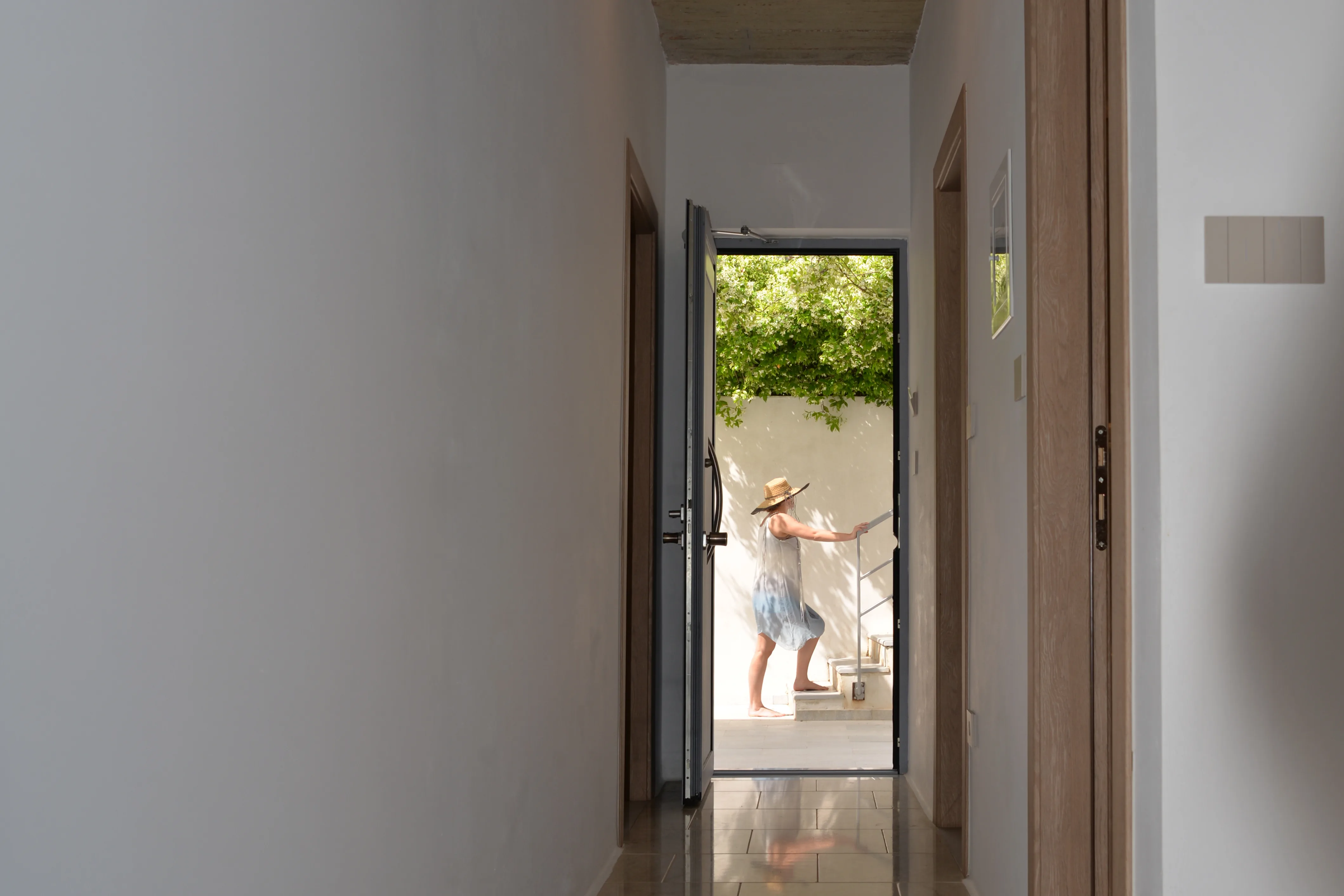 Corridor opening to a bright terrace with a guest at the rail