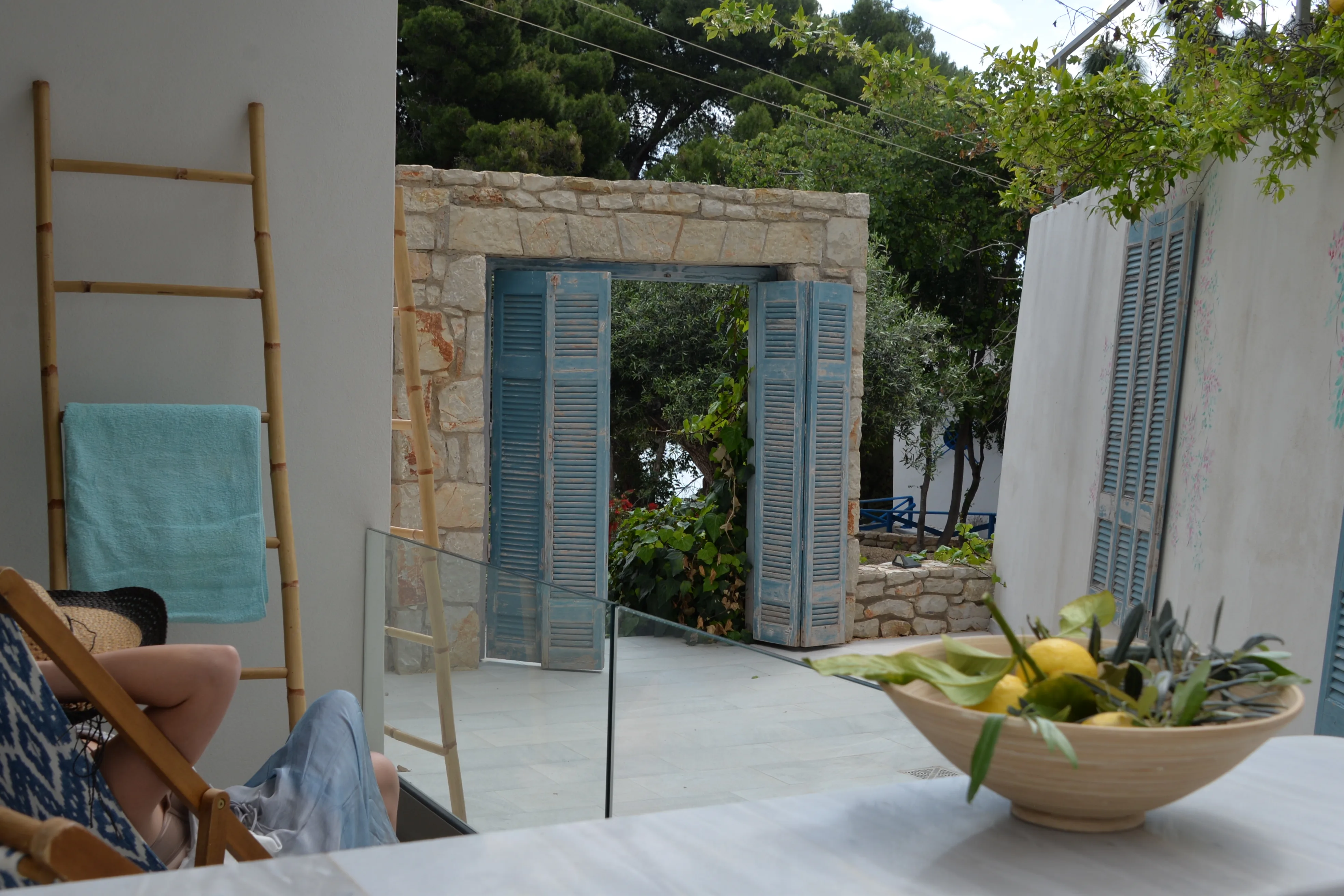 Stone gateway with blue shutters and a wooden ladder in the garden