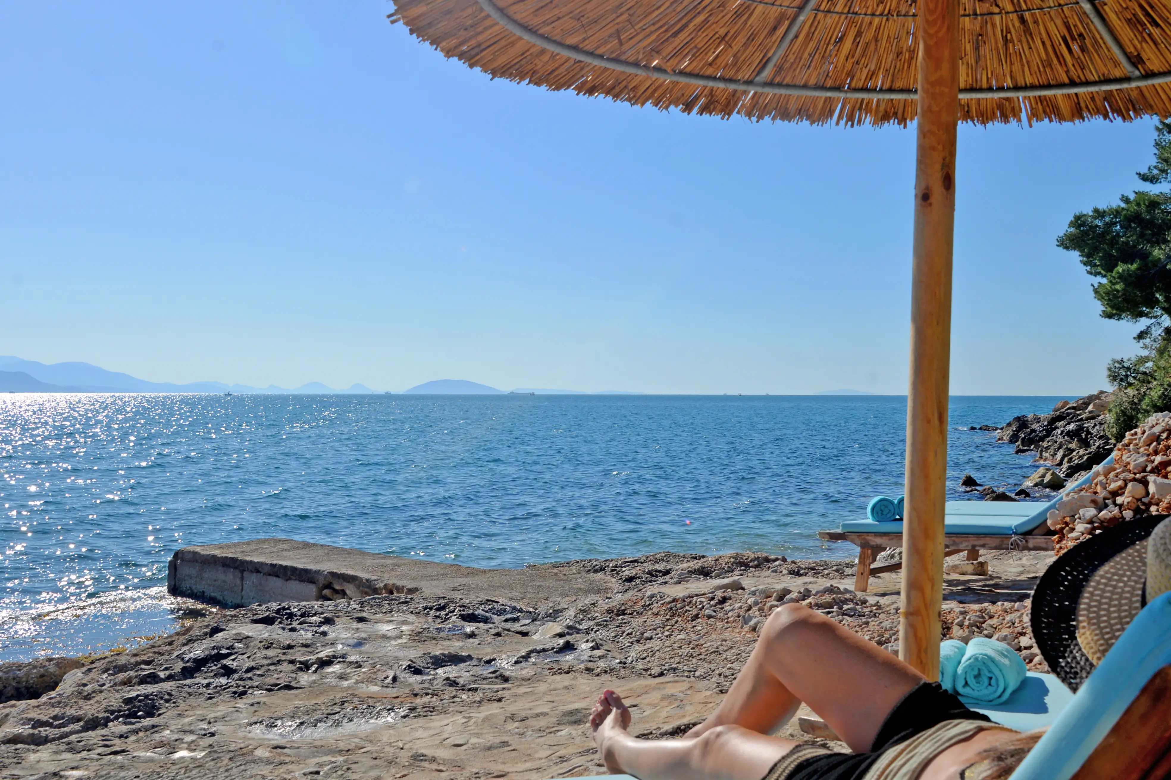 Reed umbrella and loungers on the rocky shore below the property