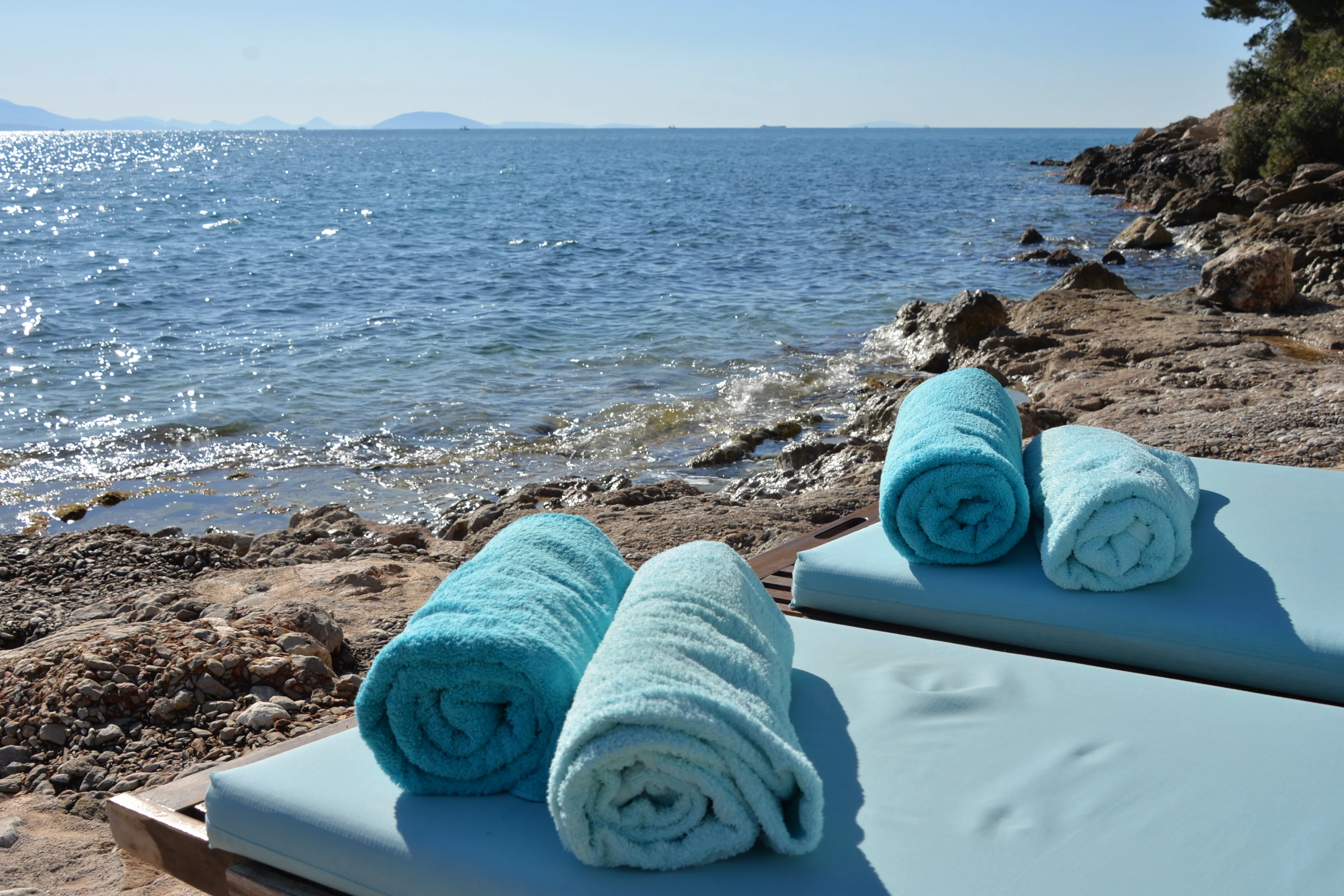 Rolled turquoise towels on a daybed by the sea