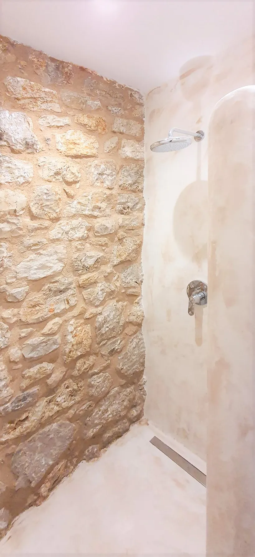Stone-walled shower with polished fittings