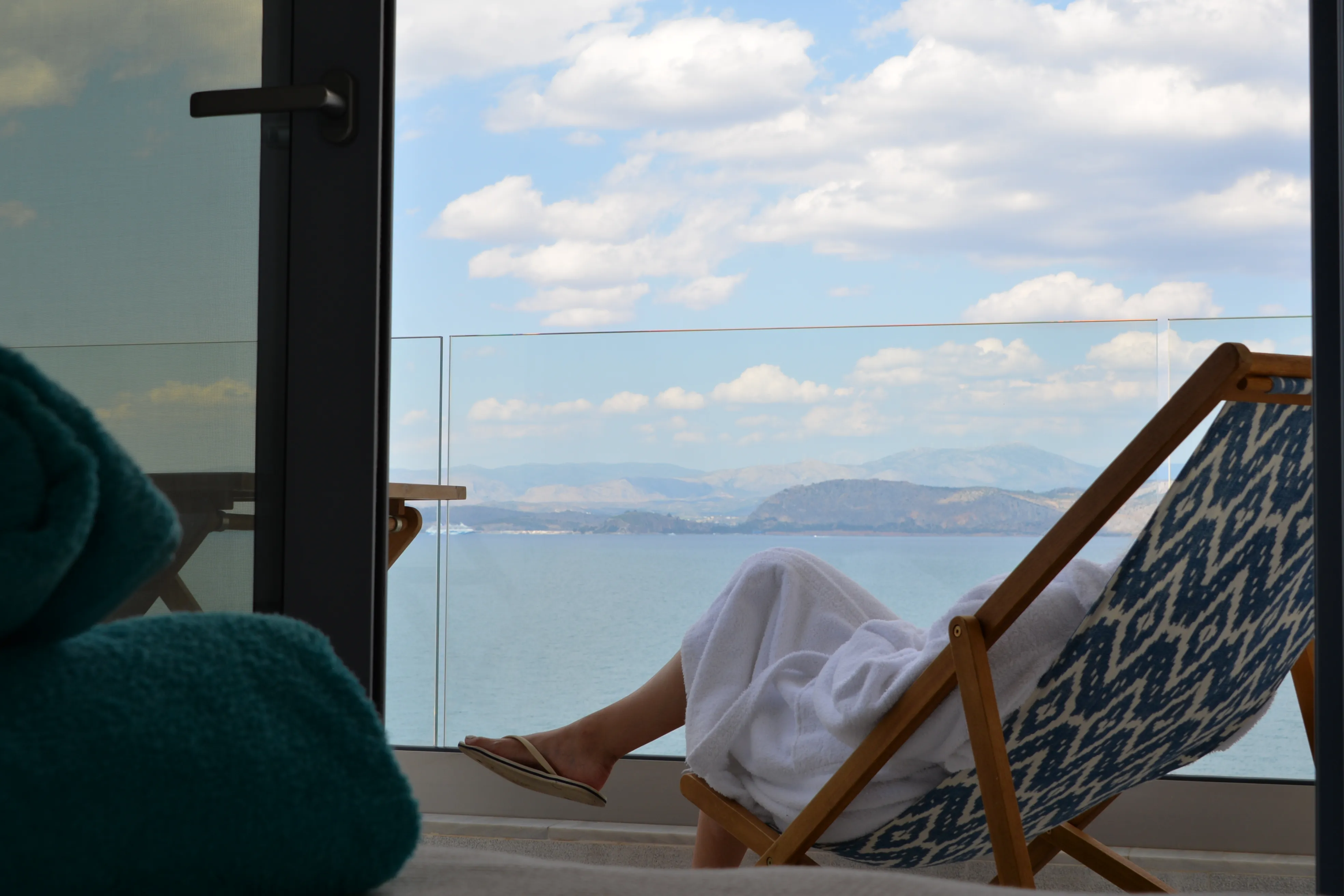 Guest resting on the Eos balcony deckchair above the gulf