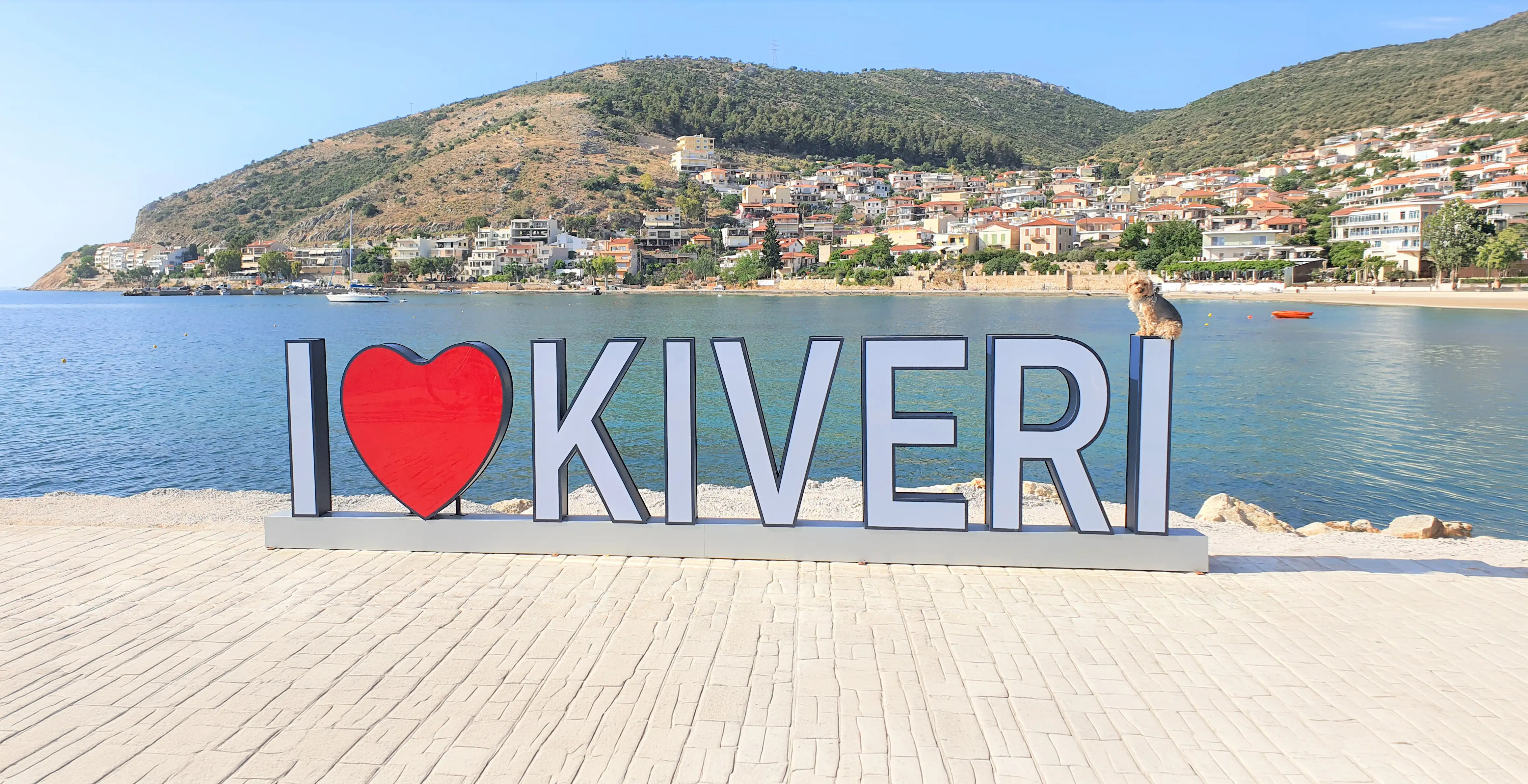 The “I love Kiveri” sign on the village waterfront, with houses on the hillside behind